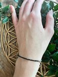Zwarte facet geslepen kristallen armband met zilverkleurige details om een pols.