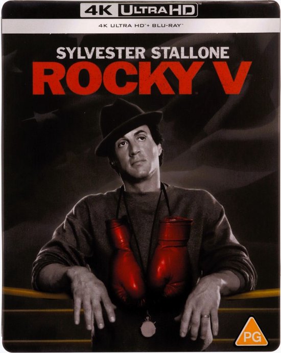 Sylvester Stallone als Rocky in "Rocky V", met rode bokshandschoenen om zijn nek en een hoed.