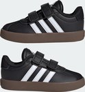 Twee zwarte Adidas kindersneakers met witte strepen en klittenbandsluiting, op bruine zolen.
