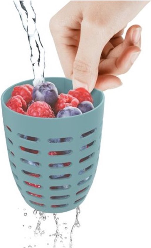 Main lavant un panier bleu avec des fraises, myrtilles et framboises sous l'eau courante.
