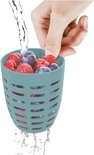 Main lavant un panier bleu avec des fraises, myrtilles et framboises sous l'eau courante.