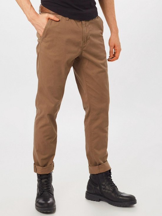 Close-up van de broekspijpen van een bruine chino broek met opgerolde zoom.