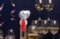 Grijze olifant wijnstopper bovenop een fles, met feestelijke achtergrond en wijnglazen.