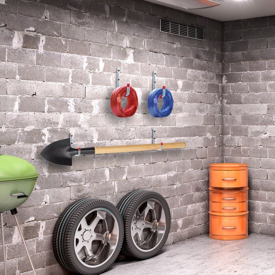 Een schuur met gereedschap, banden en opbergcontainers aan een betonnen muur.
