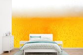 Behang - Fotobehang Close up van een goudkleurig biertje - Breedte 600 cm x hoogte 400 cm