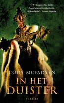 Close-up van een hand die een versierd kruis vasthoudt. De tekst 'Cody McFadyen In Het Duister Thriller' staat in grote letters op de kaft.