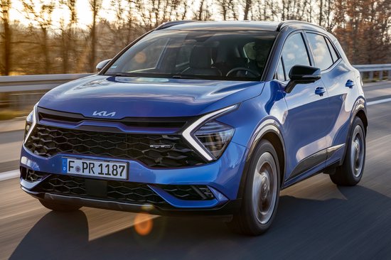 Een blauwe Kia Sportage rijdt op een weg.