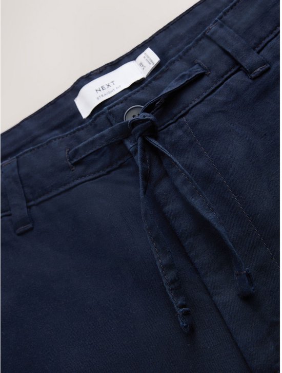 Label met tekst 'NEXT STRAIGHT FIT' aan de binnenzijde van de tailleband van de donkerblauwe chino.