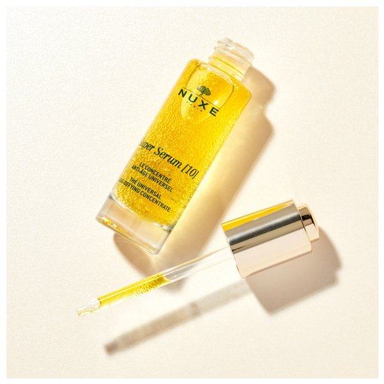Nuxe Super Serum flesje met gouden serum en druppelaar op een lichte achtergrond.
