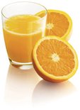 Een glas versgeperst sinaasappelsap met twee halve sinaasappels ernaast.