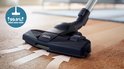 Buse d'aspiration Philips noire avec accents bleus sur un parquet, avec des flèches indiquant le flux d'air.