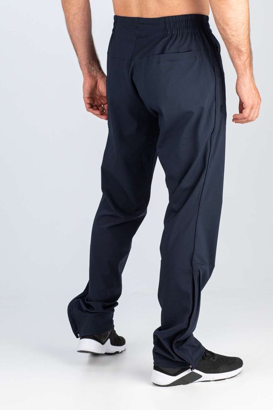 Donkerblauwe sportbroek, van achteren gezien. Elastische tailleband, ritsen onderaan de broekspijpen.