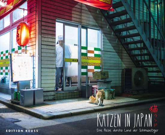 Een oranje kat ligt voor een Japanse eetgelegenheid met een man in een witte koksmuts achter het raam. De titel 'Katzen in Japan' is zichtbaar.