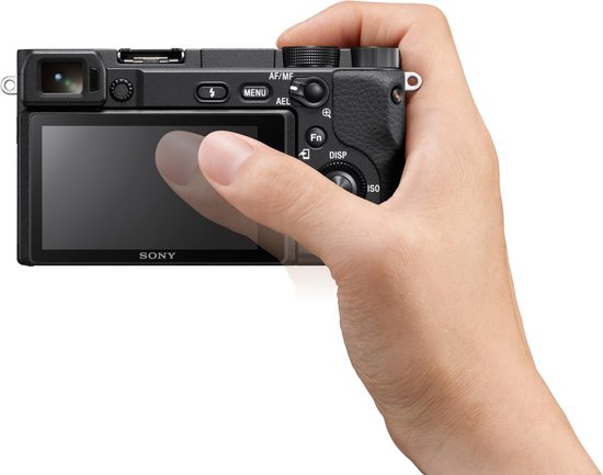 Hand houdt zwarte Sony A6400 camera vast, vinger op touchscreen.