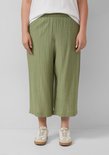 Model draagt olijfgroene culotte met crinkle stof en witte sneakers, close-up van de broekspijpen.