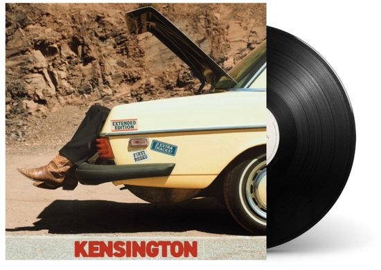 Zwarte vinylplaat met albumhoes: zittend op de achterklep van een gele auto, met cowboylaarzen en spijkerbroek. "KENSINGTON" in rode letters.