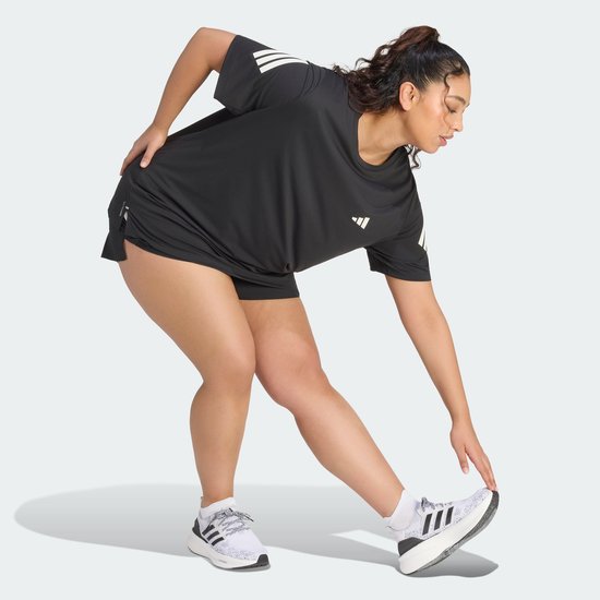 Model in zwart Adidas sportshirt met witte strepen, strekkend naar de enkel.