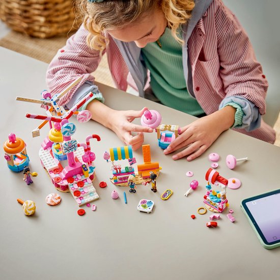 Een kind bouwt aan het LEGO Friends Candy & Cupcake Reuzenrad met snoepjes en kraampjes.