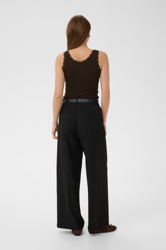 Model van achteren gezien in een bruine, nauwsluitende tanktop met kanten rand en zwarte wijde broek.