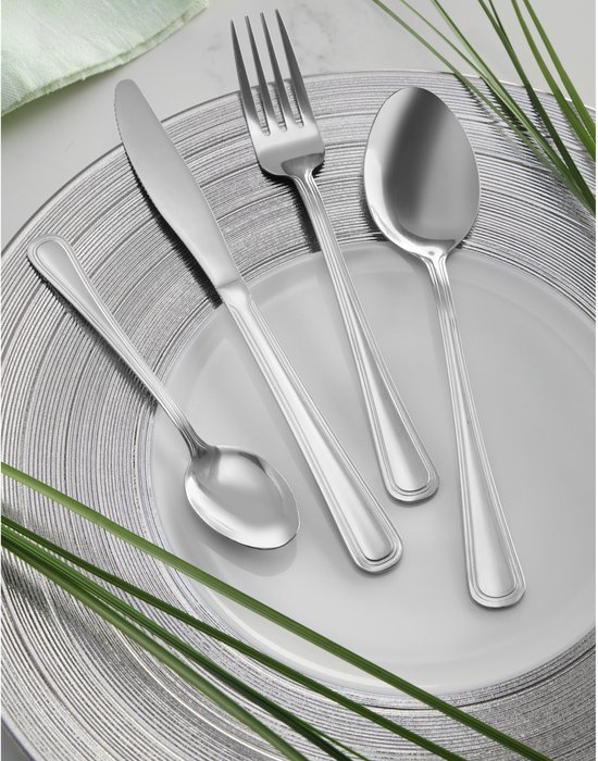 Un couteau, une fourchette et deux cuillères sur une assiette, décorés d'une serviette verte et de plantes.