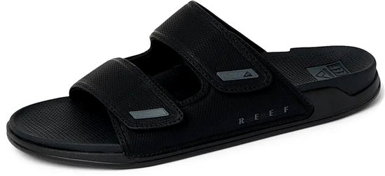 Zwarte synthetische slipper met twee banden en klittenbandsluiting, met REEF logo op de zool.