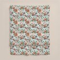 Een gevouwen lichtgroen dekbed met een print van roze en oranje bloemen en groene bladeren.
