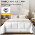Wit dekbed op een bed met twee nachtkastjes en een lamp, 'Frisse, ademende slaap'.