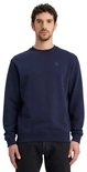 Man met donkerblauwe sweater met ronde hals en een klein ruitvormig logo op de borst.