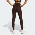 Achterkant van vrouw in donkerbruine legging, middenhoog getailleerd, witte sneakers.