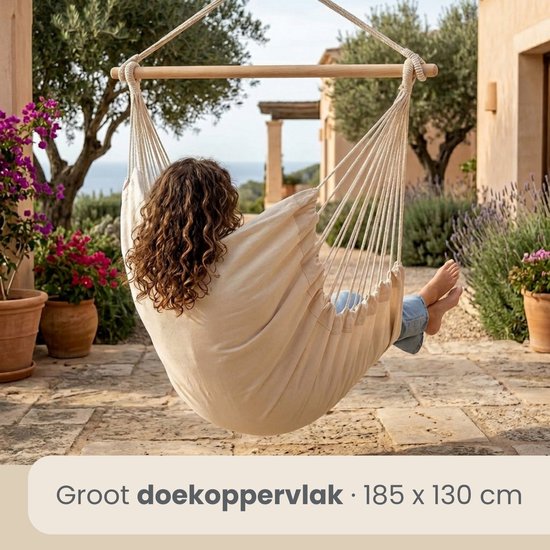 Vrouw met krullend haar in een crèmekleurige hangstoel, zicht van achteren.
