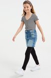 Meisje in een gestreepte top, spijkerrok en zwarte legging.