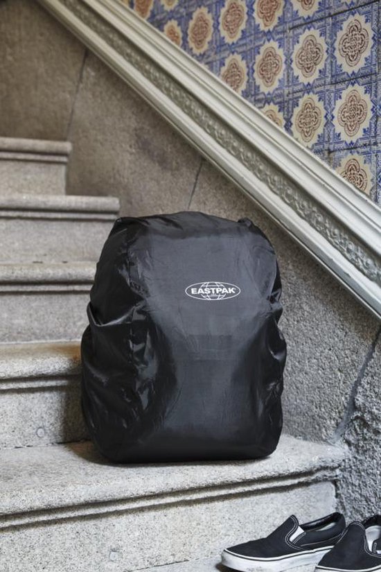 Zwarte Eastpak regenhoes over een rugzak, op een trap met tegels.