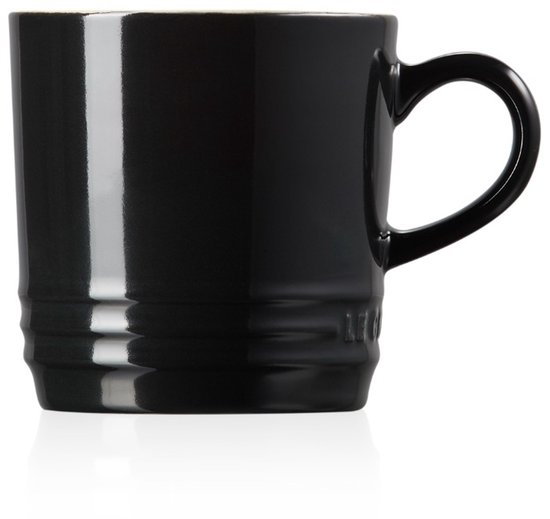 Mug Le Creuset noir à l'intérieur crème et anse noire, posé sur un fond blanc.