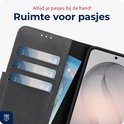 Zwart lederen telefoonhoesje, opengeklapt met drie pasjes en een bankbiljet zichtbaar.
