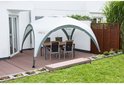 Een Coleman partytent met tafel en stoelen op een houten terras.