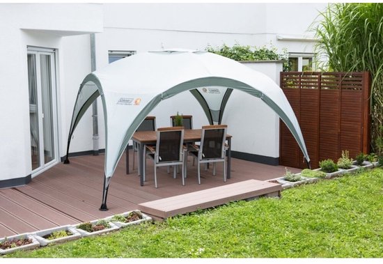 Een Coleman partytent met tafel en stoelen op een houten terras.