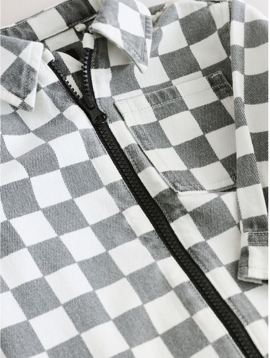 Close-up van de kraag en de zwarte rits van het grijs-wit geblokte overshirt.