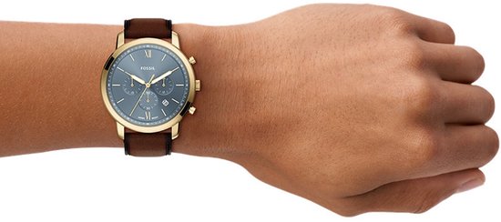 Gouden Fossil horloge met blauwe wijzerplaat en bruine leren band gedragen om een pols.