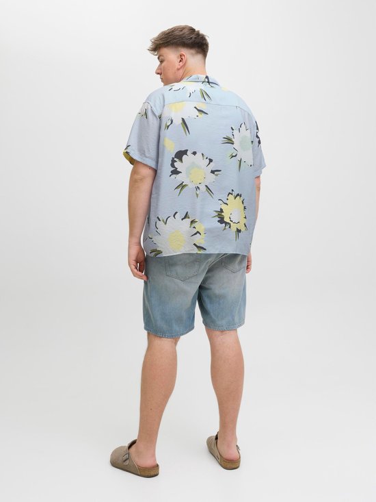 Blauw kort hemd met grote witte en gele bloemenprint, gedragen door een man.