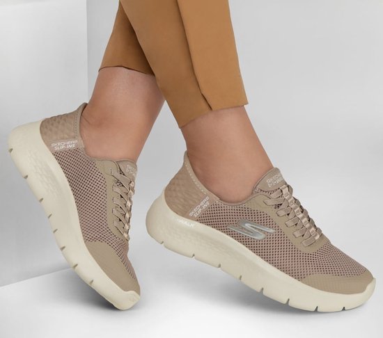 Voeten in taupe Skechers GO WALK sneakers met mesh bovenwerk, zilveren S-logo en witte zolen.