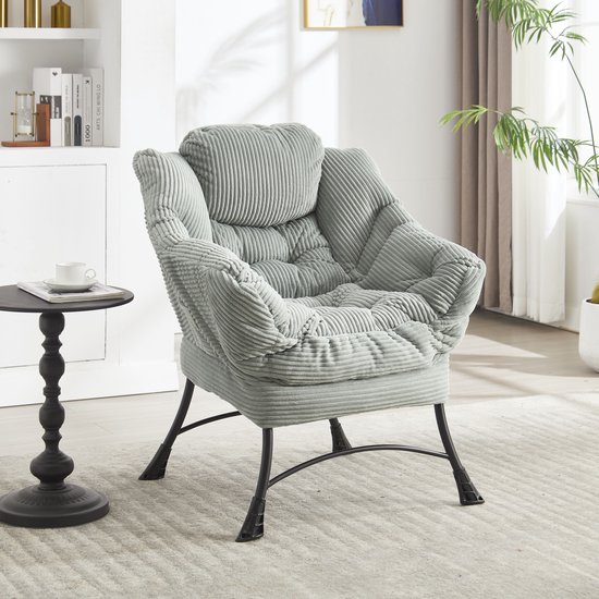 Lichtgroene corduroy lounge stoel met zachte vulling en zwarte metalen poten.