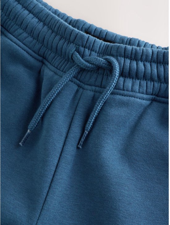 Detail van blauwe joggingbroek met trekkoord en elastische tailleband.