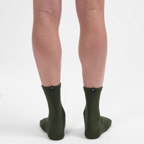 Achterkant van donkergroene fietssokken, tot halverwege de kuit, met een rond zwart logo aan de achterkant.