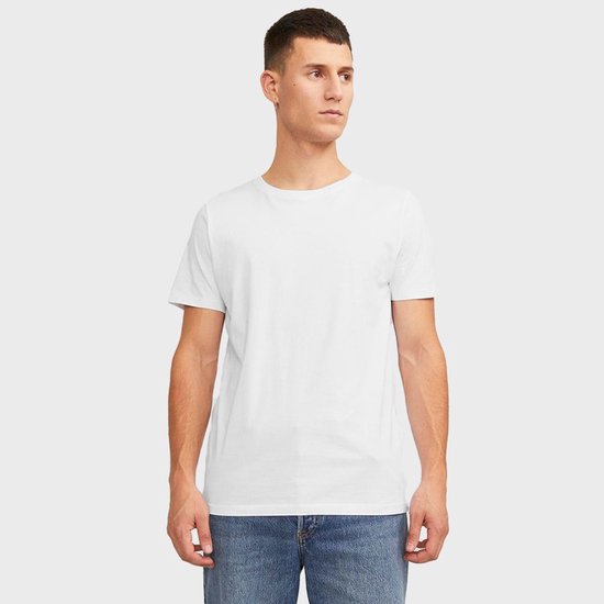 Man in een wit T-shirt en blauwe spijkerbroek, staand naar links gedraaid.