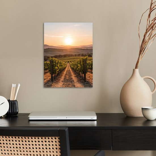 Een poster van een wijngaard bij zonsondergang boven een bureau.