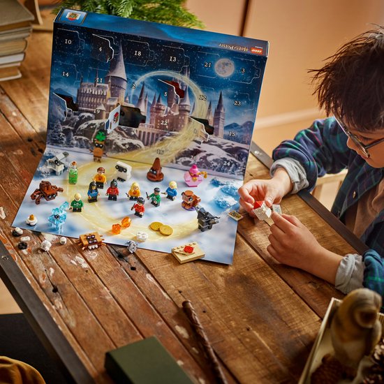 Un garçon ouvre un Calendrier de l'Avent LEGO Harry Potter avec des surprises quotidiennes sur une table en bois.