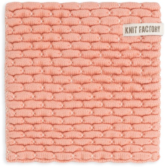 Gebreide onderzetter van Knit Factory in perzikkleur met een 3D-ribbelpatroon en kleine witte stipjes. Label 'KNIT FACTORY' zichtbaar.