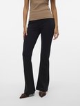 Vrouw in beige top en zwarte flared broek, schoenen zichtbaar.