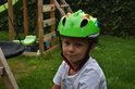 Groene dinosaurus kinderhelm met grote blauwe ogen en witte tanden. Gedragen door een jongen.