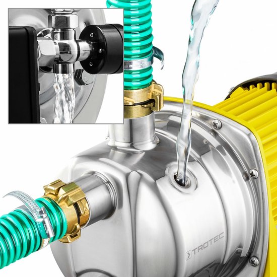 Close-up van water dat uit een groene slang stroomt en een RVS hydrofoorpomp met gele motorbehuizing.